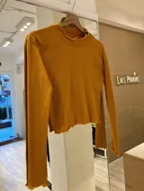 Remera de morley color mostaza, de manga larga, con cuello alto fruncido y terminaciones fruncidas en las mangas.