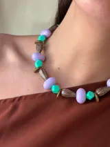 Collar corto con cuentas de cristales checos lilas, cuentas acrílicas turquesas y cuentas de bronce con diseño abstracto. Se cierra con cadena de acero quirúrgico y ganchito para regular el largo.