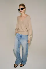 Jersey de punto metalizado color beige, con escote en V y manga larga.