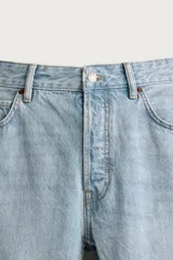 Jeans regular fit de mezclilla negra con efecto lavado, corte recto y tiro medio. Cuenta con diseño de cinco bolsillos y cierre frontal con cremallera y botón.