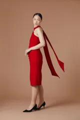 Vestido midi de crepe elastizado color rojo, con escote halter, detalle metálico en el cuello y lazo largo que cae desde el hombro. Diseño ajustado al cuerpo con frunces laterales.