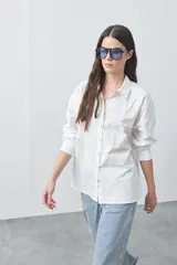 Camisa de manga larga de algodón en color blanco, con cuello clásico, cierre frontal de botones y silueta relajada.