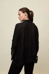 Camisa blanca de calce relajado, con cuello clásico, mangas 3/4 y cierre frontal de botones. Presenta bordados florales en relieve y detalles de crochet calado en los puños y el ruedo.