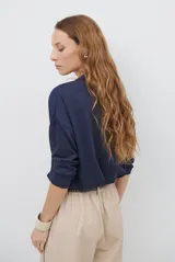 Blusa de color azul oscuro, con cuello mao y escote en V. Presenta mangas largas con puños abotonados y un corte recto y holgado.