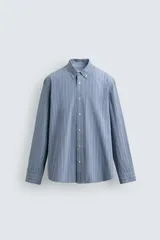 Camisa de corte regular fit confeccionada en tejido compacto de algodón. Presenta un diseño de rayas verticales, cuello abotonado, manga larga con puños abotonados y cierre frontal con botones.