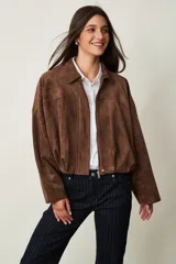 Campera de gamuza marrón, de corte oversize con hombros caídos, cuello camisero, cierre frontal de cremallera y puños y dobladillo elásticos.