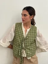 Chaleco verde claro con diseño acolchado y estampado a cuadros, sin mangas y con tiras para anudar en el frente.