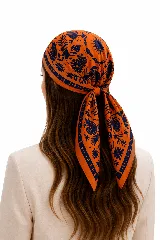 Pañuelo cuadrado de tela con estampado botánico y geométrico en tonos naranja y azul marino.