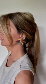 Aros con diseño de flor multicolor, compuestos por pétalos metálicos en tonos vibrantes y centro decorado con pequeñas perlas.