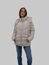 Campera puffer color beige con cierre frontal y bolsillos laterales con cierre. Tiene capucha desmontable y relleno acolchado.