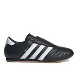 Championes Adidas modelo Taekwondo, color negro con las tres bandas características en blanco. Presentan un diseño sin cordones con empeine acolchado y suela de goma color caramelo.