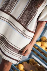 Vestido corto tejido a rayas horizontales en tonos beige y blanco, con cuello redondo y mangas cortas.