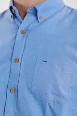 Camisa de vestir blanca de manga larga, con cuello abotonado, bolsillo frontal y botones en tono madera.