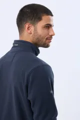 Buzo de abrigo de polar color negro, con cuello alto, medio cierre metálico frontal y bolsillos laterales con cierre. Presenta logo a tono bordado en el pecho.