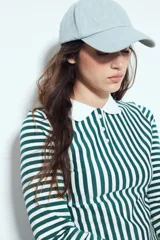 Remera de manga larga a rayas verticales verdes y blancas, con cuello polo y cierre frontal de botones. Presenta un diseño ajustado al cuerpo.