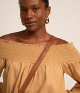 Blusa color ocre de tricolina con escote hombro a hombro con lastex, mangas largas con lastex en los puños y regulador en la parte baja.