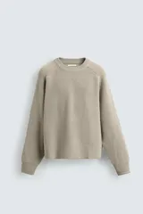 Jersey de punto con diseño boxy fit, cuello redondo y manga larga. Presenta una textura acanalada y acabados en rib en puños y ruedo.