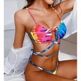 Bikini con estampado tie-dye multicolor con predominio de rosado, azul y amarillo. El corpiño es de diseño triangular con tiras largas para cruzar alrededor del torso y un lazo frontal. La bombacha es tipo tanga con tiras laterales regulables.