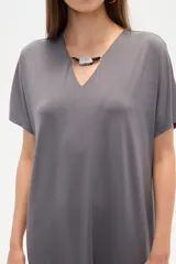 Vestido midi de corte holgado, color negro, con mangas cortas, cuello en V y detalle de cuentas decorativas en el escote.