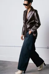 Pantalón cargo de tiro medio confeccionado en algodón, con cintura con trabillas, bolsillos delanteros y bolsillos laterales de plastrón con solapa. Cierre frontal con cremallera, botón y ganchos metálicos.