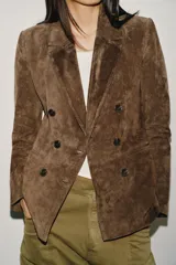 Blazer de ante color marrón, con cuello solapa, hombreras, manga larga y cierre frontal cruzado con botones. Cuenta con bolsillos delanteros de doble vivo.