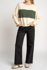Sweater color crema con una franja horizontal verde en el pecho, de corte oversize y mangas largas.