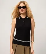 Top sin mangas de punto color celeste claro, con cuello polo ribeteado con dos líneas blancas y cierre frontal de tres botones. El tejido presenta un patrón de trenzas verticales.