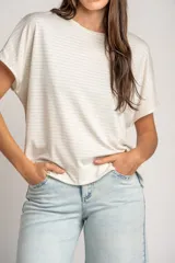 Remera oversize color crudo con sutiles rayas horizontales plateadas, mangas cortas caídas y cuello redondo.