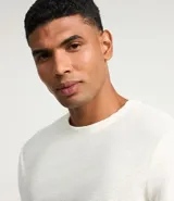 Remera de manga larga con cuello redondo y textura acanalada, confeccionada en una mezcla de poliéster y algodón.