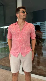 Camisa de fibrana color rosa con estampado de líneas verticales blancas, de manga corta y cuello clásico.
