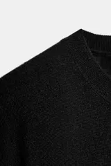 Jersey de punto liso color verde, con cuello redondo y manga larga. Confeccionado en lana suave.