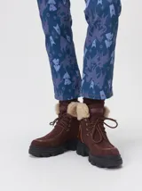 Borcegos de caña baja con diseño robusto, confeccionados en una combinación de gamuza y cuero sintético en tonos verde oliva. Presentan suela track de goma dentada en color suela, cordones al tono con ojalillos amarillos y cuello acolchado para mayor confort.