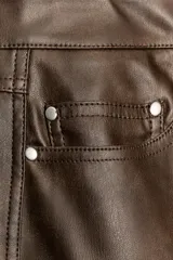 Pantalón de tiro medio confeccionado en tejido efecto piel, con diseño de cinco bolsillos y cierre frontal con cremallera y botón.