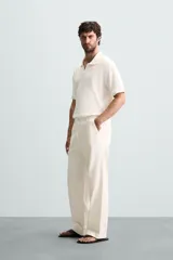 Polo de tejido canalé en color blanco, con cuello solapa y abertura frontal en V, de manga corta y corte regular.