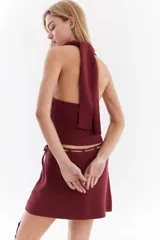 Top bordó de punto con lurex, escote en V profundo estilo halter y diseño sin mangas.