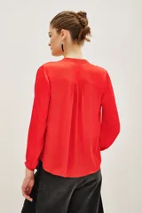 Camisa de satén color rojo, con cuello mao y escote en V, mangas largas con puños elásticos y detalle de frunces en los hombros.