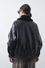 Campera de cuero sintético con acabado satinado, silueta relajada y elástico en la cintura. Presenta cuello con textura de piel sintética, cierre frontal y bolsillos laterales.