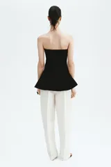 Top strapless largo en punto tupido color negro, con costuras enlazadas y peplum acampanado.