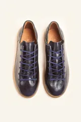 Zapatilla de cuero vacuno color azul marino, con cordones azules y suela de caucho color caramelo.