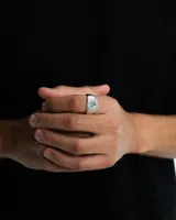 Anillo plateado con forma cuadrada y una estrella grabada en el centro.