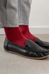 Mocasines de cuero color dorado con acabado texturizado, diseño clásico de punta redondeada y costuras visibles en el empeine. Cuentan con suela plana y flexible.