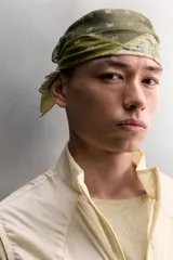Bandana cuadrada confeccionada en tejido ligero de mezcla de ramio y algodón, con diseño de patchwork que combina paneles con estampados florales y paisley en tonos amarillo, mostaza y verde militar.