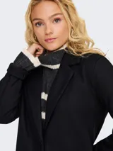 Blazer largo de corte recto y estilo minimalista, con cuello solapa, cierre frontal de dos botones y dos bolsillos frontales de parche.