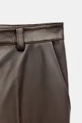 Pantalón de tiro medio confeccionado en 100% piel de color marrón, con diseño flare y costuras decorativas.