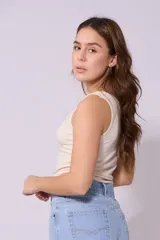 Musculosa color crema de corte ajustado, con cuello redondo y detalle de cadena dorada en el escote.