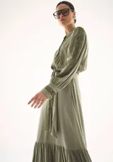 Falda larga de corte fluido en color verde oliva, con diseño de volado en el ruedo y detalle de encaje delicado en el borde inferior.