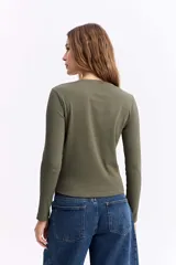 Remera de manga larga con cuello redondo y ajuste al cuerpo, confeccionada en tejido de algodón con textura acanalada.