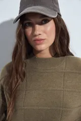Sweater de punto gris con cuello a la base y diseño de trama geométrica en relieve. Presenta un calce relajado con mangas largas y puños tejidos.
