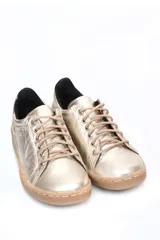 Deportivo de cuero liso color caramelo, con cordones beige y suela blanca. Presenta un detalle metalizado plateado en el talón.