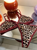 Conjunto de lencería compuesto por un corpiño triangular y una bombacha tipo vedetina, ambos con estampado animal print y bordes en color bordó.